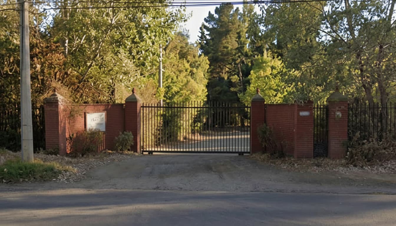 Portón de acceso al condominio, con pilares de ladrillo y reja metálica